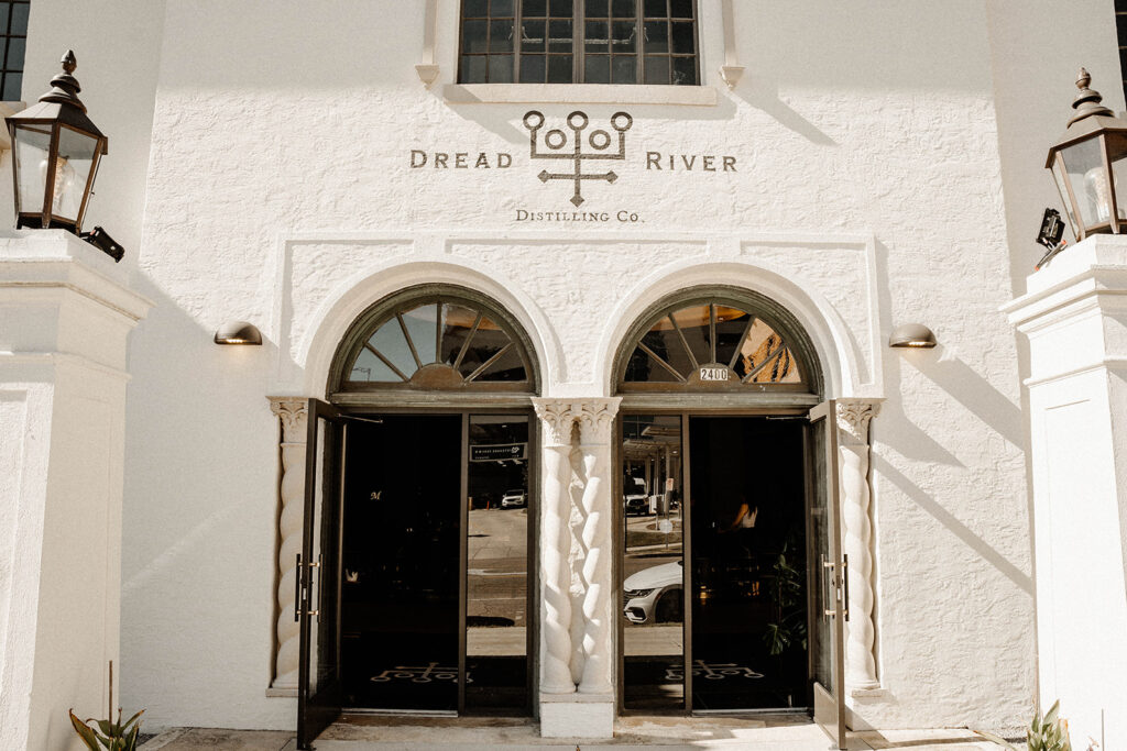 The entrance to the Dread River Distilling Co. with a white facade and arched doorways.