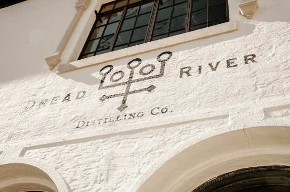 Dread River Distilling Co. logo on a white brick wall.