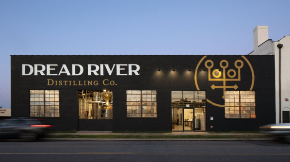 Dread River Distilling Co. building with illuminated signage at dusk.