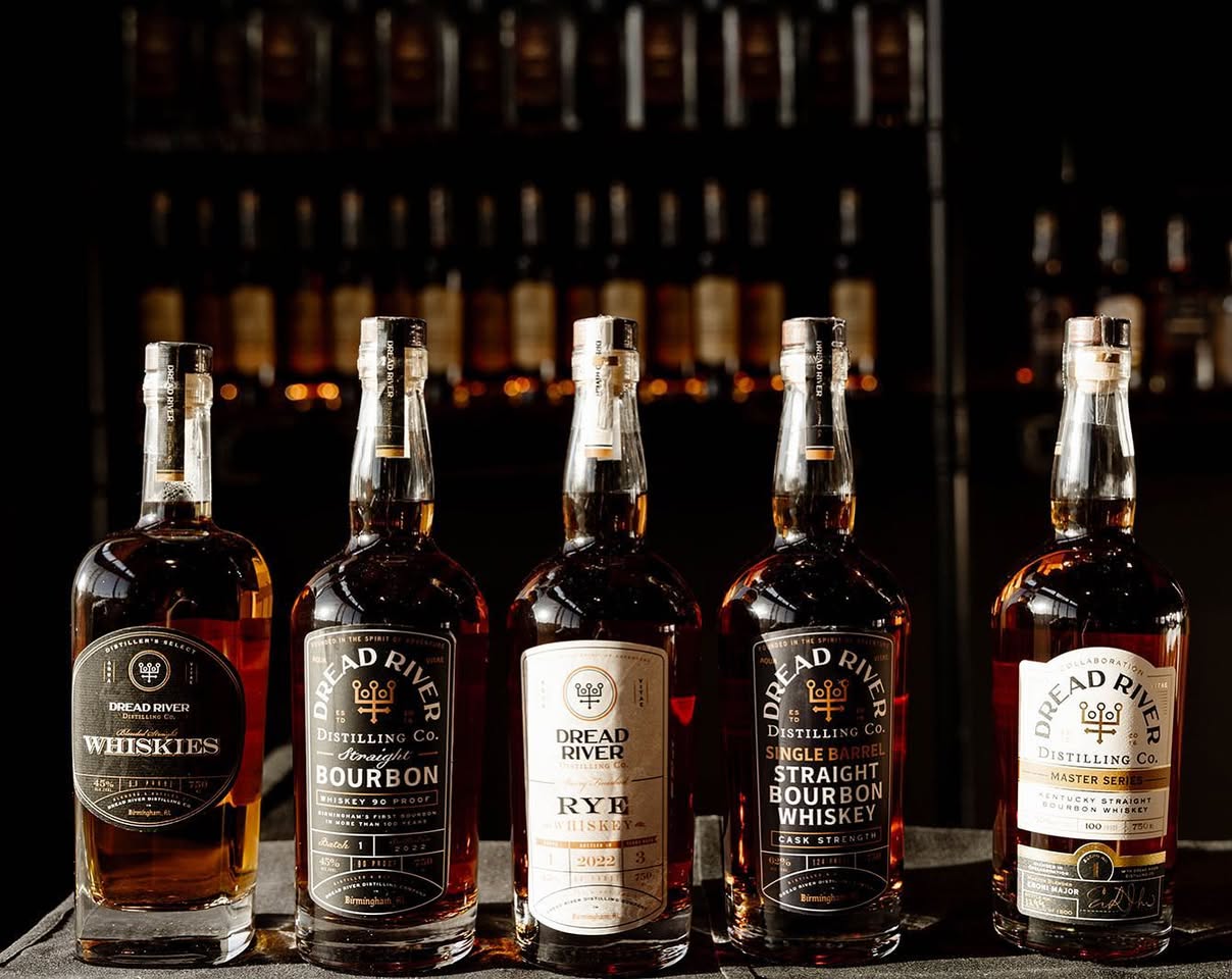 Different whiskey styles displayed in amber-lit tasting glasses and bottles during a premium whiskey tasting experience.