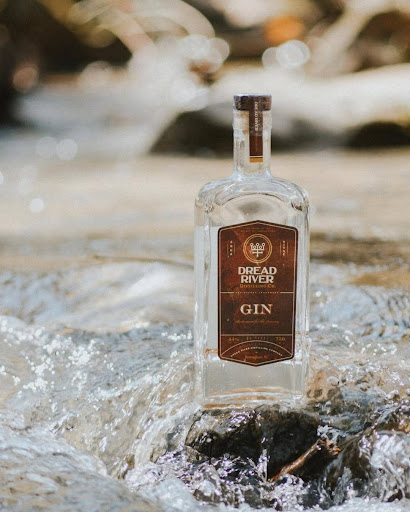 A bottle of fine gin from Dread River Distilling Co. displayed on a bar counter next to a cocktail.