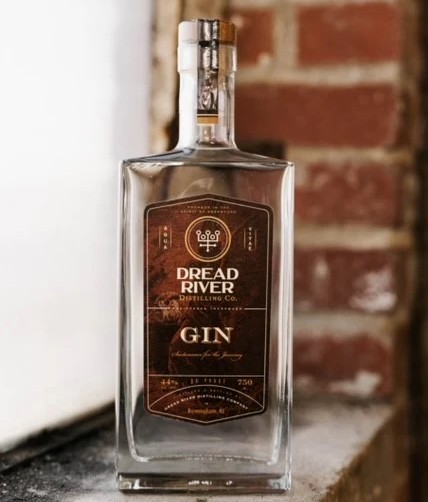 Dread River Gin bottle with copper-accented label placed against a brick background in Birmingham, Alabama.

