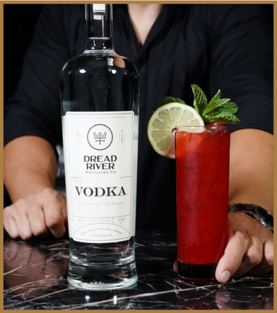 A bottle of Dread River Vodka beside a cocktail garnished with lime and mint, showcasing the brand's craftsmanship.