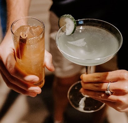 Two people flaunt glasses of sip-worthy cocktails from Dread River.