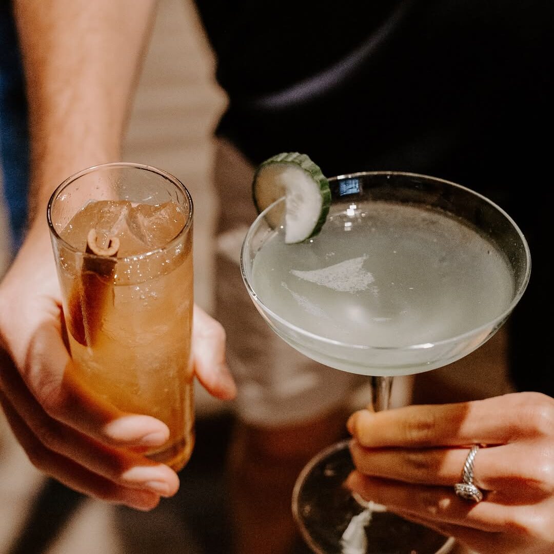 Two people clink their glasses of whiskey cocktails made with whiskey from Dread River.
