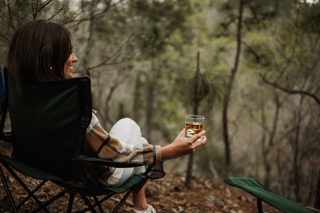 A woman sitting outdoors with a glass of Dread River rum in the chilly weather.