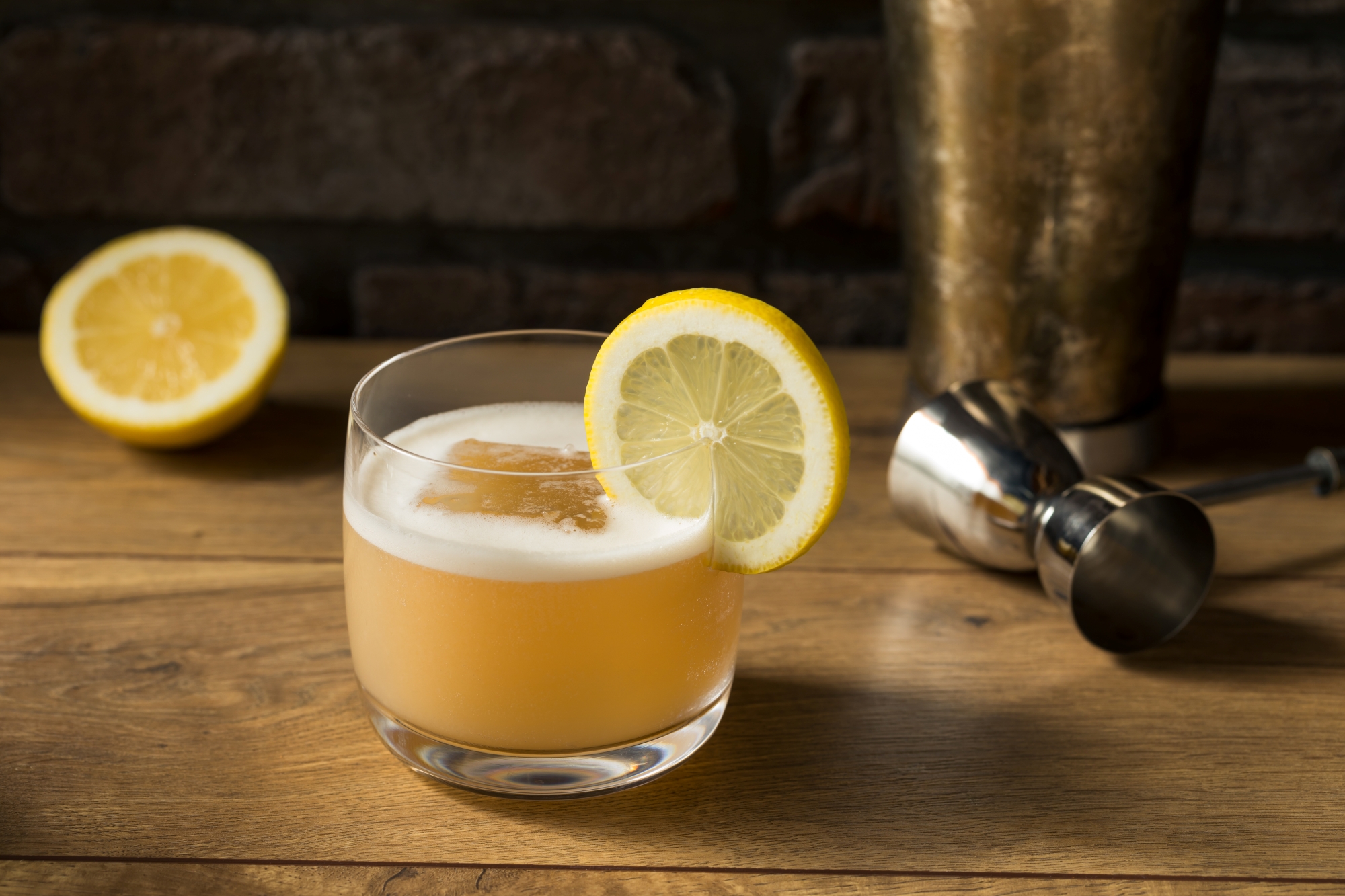 A classic whiskey sour with foamy top and lemon wheel garnish on a bar, from Dread River wine distillery.