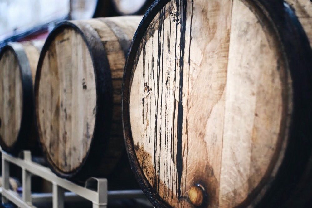 Oak barrels aging inside Dread River Distillery’s warm Alabama rickhouse warehouse.