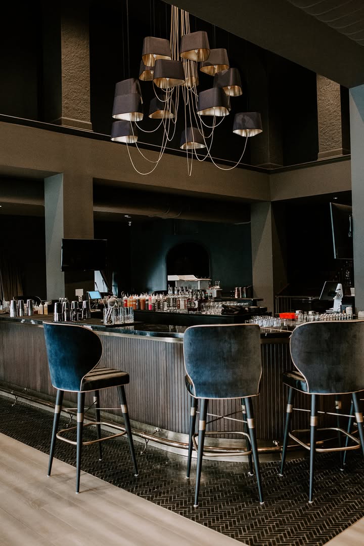 Interior of Dread River Distilling Co. tasting room with curved bar, stools, and chandelier lighting