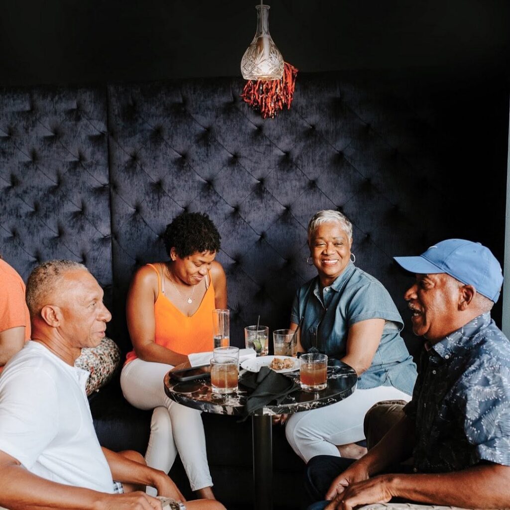 Friends enjoying cocktails together around a table in the Dread River Distilling Co. lounge.